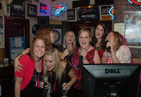 A group of women singing karaoke at Joe's Tavern at a PartyMasterz event