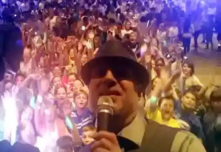 DJ Tom having fun with the kids at a school dance behind him