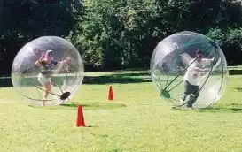 people running inside giant hamster balls at a park