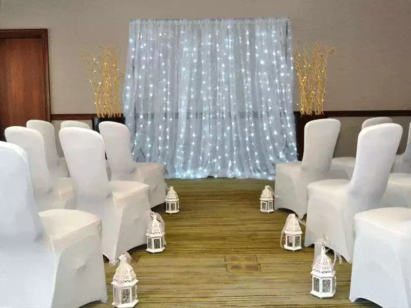 ceremony seating area with lighted curtain and white lanterns