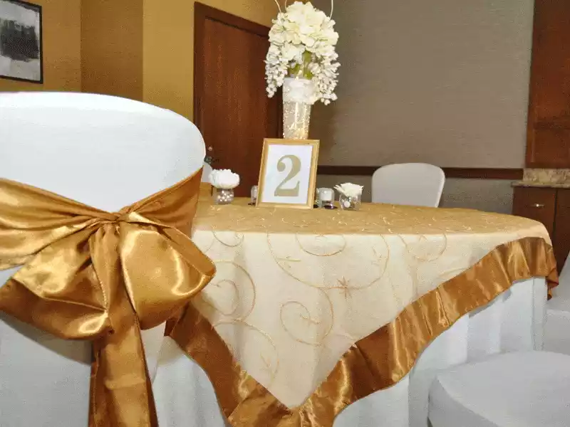Gold table linen overlay and gold chair sash decor