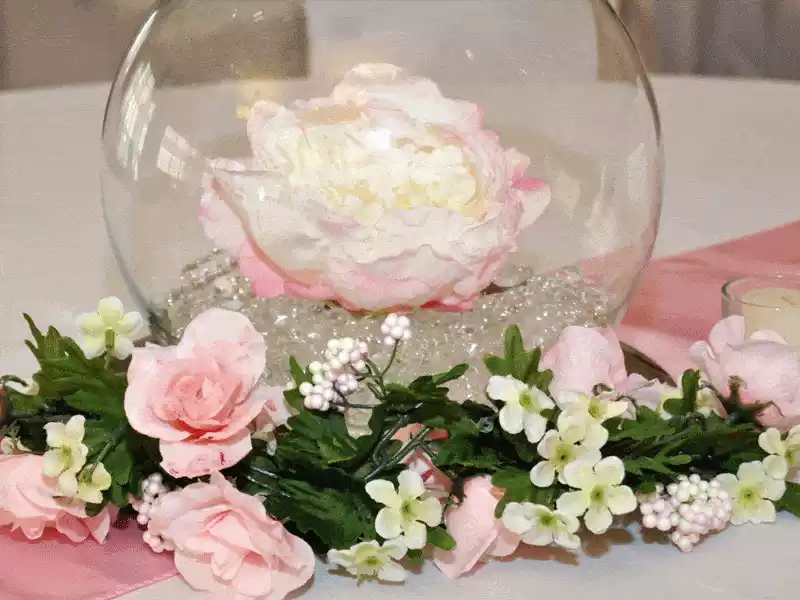 Pink flower in glass fishbowl with pink and green garland floral wreath decor