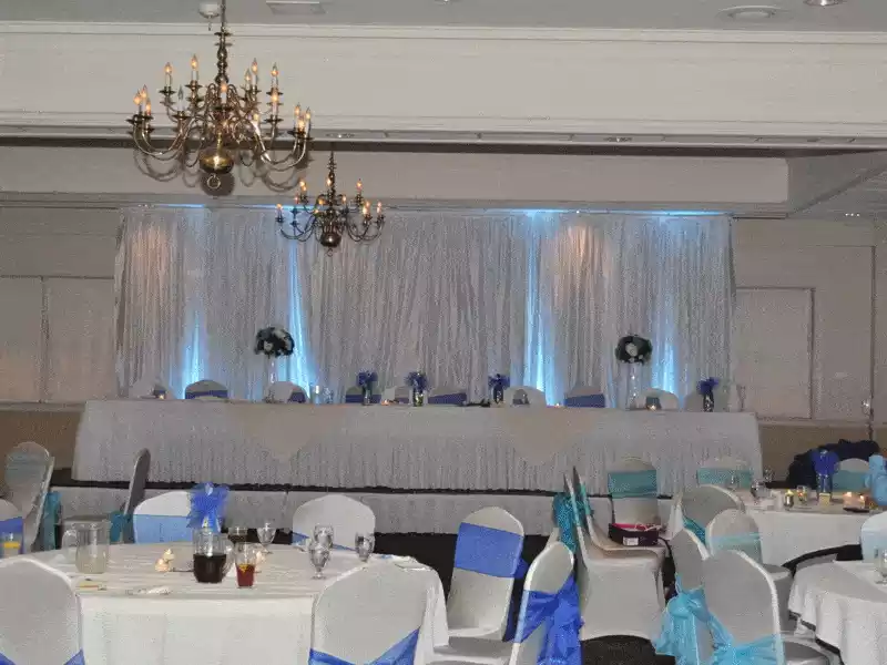 Drapery backdrop with blue uplighting and chair sashes