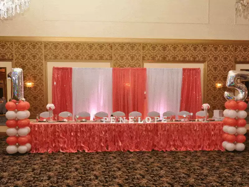 Coral and white decor for a quinceanera head table with backdrop