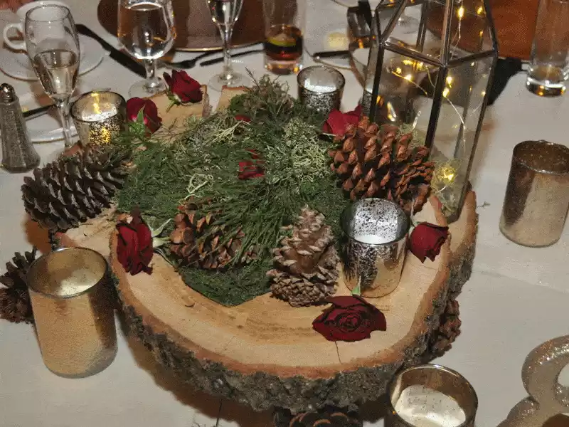 Wood cookie centerpiece with pine cones and small red roses