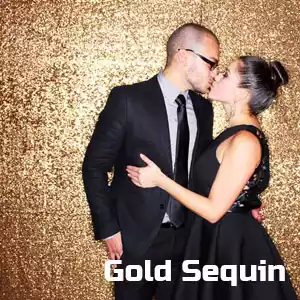 A couple kissing in front of gold sequin backdrop