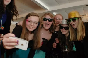 Kids wearing glasses and hats taking a group selfie