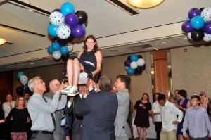 Girl being lifted in a chair during the hora at a bar mitzvah