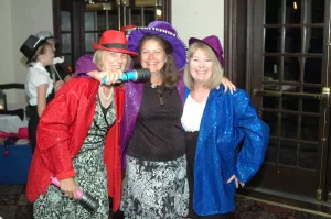 Women dressed in sequin jackets and colorful hats getting ready to go in the PartyMasterz photo booth
