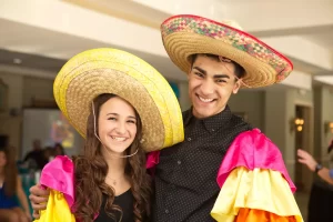 Two young people wearing sombreros and conga sleeves at a PartyMasterz event