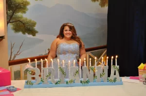 A quinceanera standing behind her candelabra at her party
