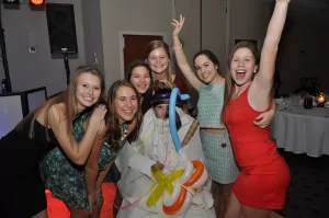 Kids pose around a mummy wrapped guest at a sweet 16