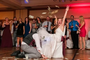 Groom retrieving garter from brides leg as she throws money in the air