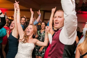 Bride and groom dancing at wedding with hands in the air