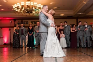 Bride and groom enjoying their first dance as bridal party watches