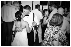 Black and white photo of groom kissing bride while slow dancing