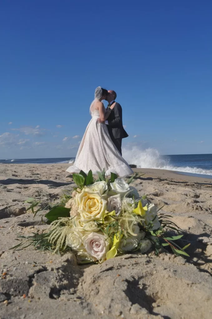 Bride and groom on a beach kissing in front of the ocean