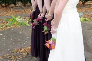 Bride and bridesmaids holding their bouquets of flowers behind them