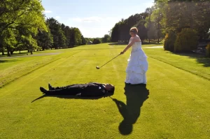 A bride hitting a golf ball off her grooms face