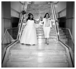 A black and white photo of a couple walking down stairs on their wedding day