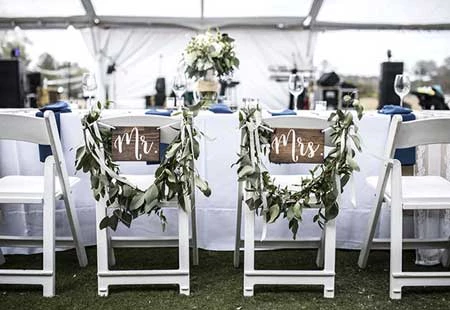 Mr. and Mrs. signs with garland on a bride and grooms chairs at their reception