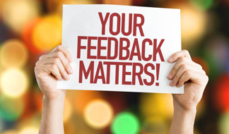 Hands holding a sign that reads your feedback matters