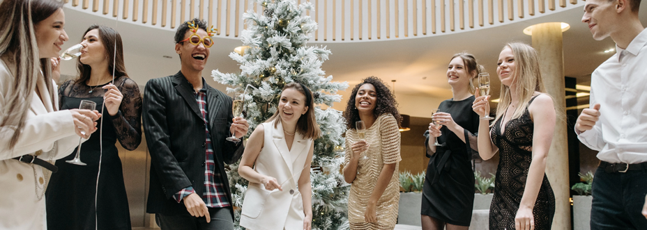 Corporate Employees in front of a christmas tree drinking champagne and celebrating the holidays at corporate party