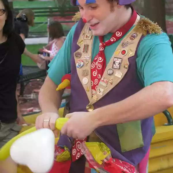 A clown making balloon art for kids at a partymasterz event