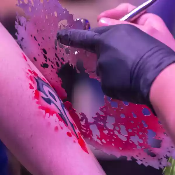 an artisit painting tattoos on an arm